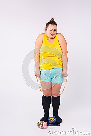 Body rejection, dissatisfaction concept. Blonde large woman with low self-esteem looking at camera, sitting on scales Stock Photo