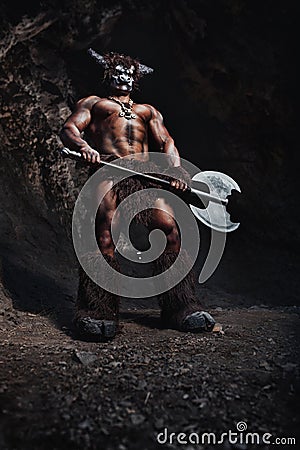 The bodyart man angry minotaur with axe in cave Stock Photo