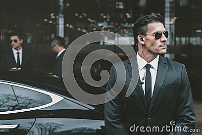 bodyguard standing at businessman car and reviewing Stock Photo