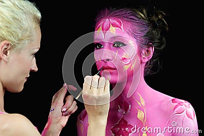 Bodypaint master in work, paints a model for a photo shoot Stock Photo