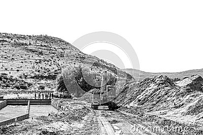 Backhoe loader clearing sand at Boegoeberg Dam. Monochrome Editorial Stock Photo