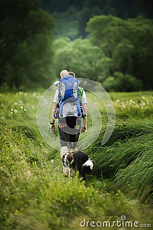 BOHEMIAN FOREST, CZECH REPUBLIC, August 2016: The Man Going through the Grass with Son in Baby Carrier. Dog Black and White Borde Editorial Stock Photo