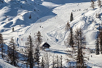 Bohinj, Slovenia - Winter view of the snowy mountain Vogel with skiers on ski slopes and wooden hut in the Alps at Triglav Stock Photo