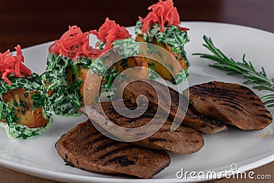 Boiled beef tongue, potato and spinach on grey table. traditional dish menu served in a restaurant, close-up Stock Photo