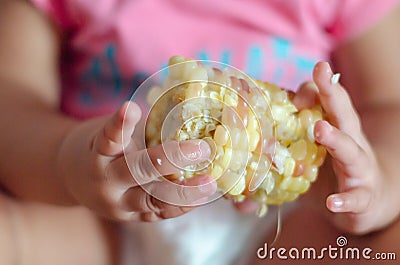 Boiled corn in the babies hands Stock Photo