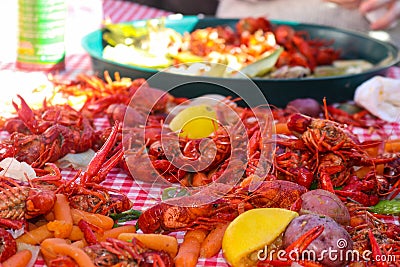 Boiled crawfish and lemons and carrots and other vegestables are piled on a table with tray for eating in background - shallow foc Stock Photo