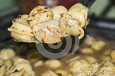 Boiled dumplings with spices on a spoon over a pot of cooked dumplings. Close up Stock Photo