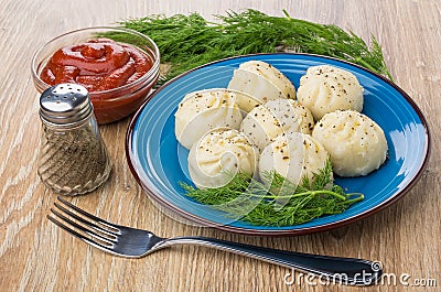 Boiled khinkali with dill in blue plate, ketchup, pepper Stock Photo