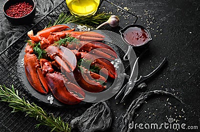 Boiled red lobster claws with spices and parsley on a black stone plate. On a black background. Stock Photo