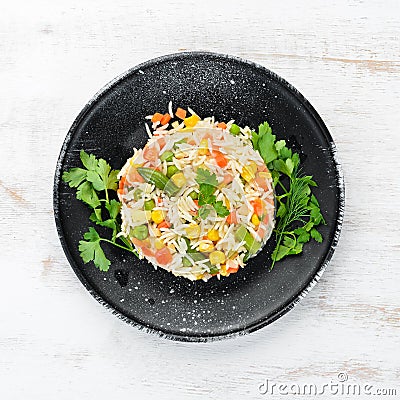 Boiled rice and vegetables. Risotto In a black plate. Top view. Stock Photo