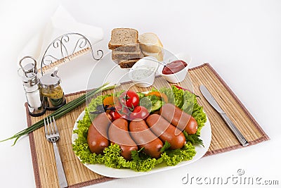 Boiled sausages with tomatoes, cucumbers and greens. Served with black or white bread. Stock Photo