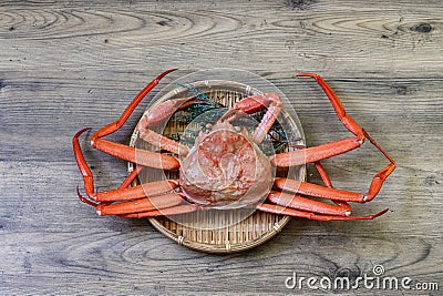 Boiled snow crab on a bamboo colander isolated on a wooden background Stock Photo