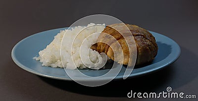 Boiled white rice with chicken cutlet wrapped in bacon on a gray background blue plate Stock Photo