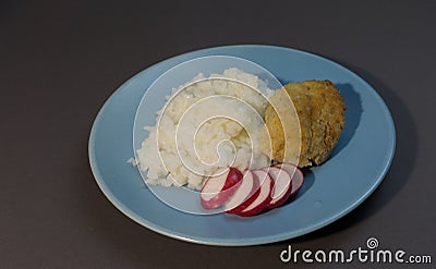 Boiled white rice with fish cutlet wrapped in bacon on a gray background blue plate. Baked fish meatball with garnish of rice and Stock Photo