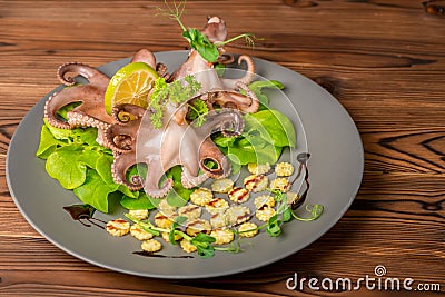Boiled whole octopus served with lime, corn, cucumber and sprig Stock Photo