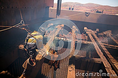Boilermaker abseiler wearing safety harness, helmet commencing oxygen lancing Stock Photo