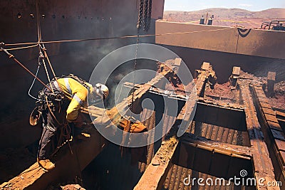 Boilermaker abseiler wearing safety harness, helmet commencing oxygen lancing Stock Photo