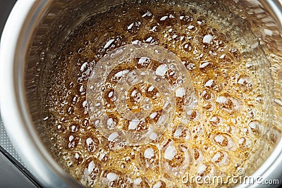 Boiling sugar syrup in a stainless steel pan Stock Photo