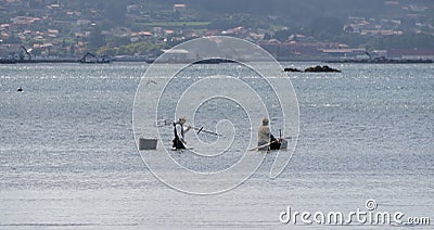 One man an a female shellfish gatherers walk along the beach. Editorial Stock Photo