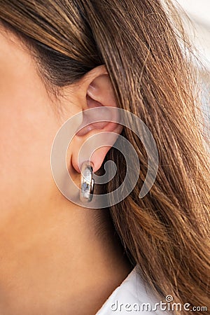 Bold Silver Hoop on a woman`s ear. Beautiful valentine`s gift Stock Photo