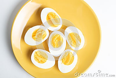 Bolied half-cut pieces of eggs on yellow plate Stock Photo