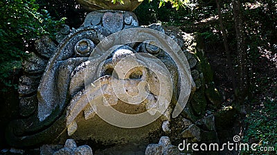 Monstrous sculpture called of Proteus and Glaucus at the Park of the Monsters of Bomarzo among trees and vegetation Editorial Stock Photo