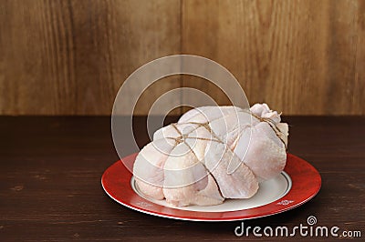 Bondage shibari raw chicken on red boarder plate on dark wood ba Stock Photo