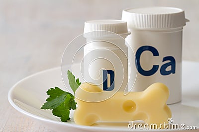 Bone shaped cheese and dietary supplements with calcium and vitamin D on plate, strong and healthy bones concept Stock Photo