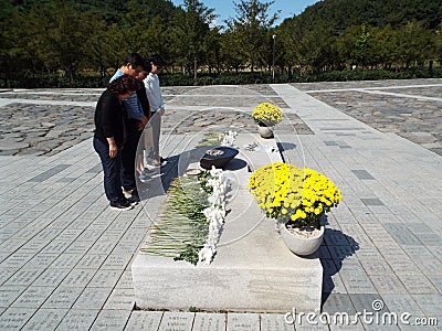 Four people pray by the mausoleum of Roh Moo-hyun, 16th president of South Korea. Bongha village Editorial Stock Photo