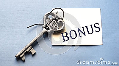 BONUS - word on white paper on a wooden background with a beautiful key Stock Photo