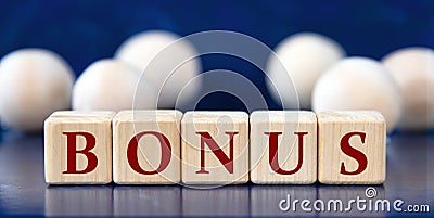 BONUS - word on wooden cubes on a blue background with wooden balls Stock Photo