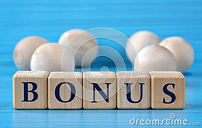 BONUS - word on wooden cubes on a blue background with wooden round balls Stock Photo