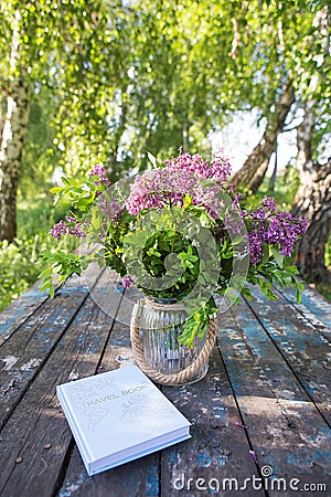 The book, a beautiful bouquet of lilacs is on an old table. Close-up Stock Photo