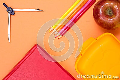 Book, compass, color pencils, red apple and lunch box on pink ba Stock Photo