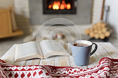 Book and cup of tea near fireplace Stock Photo