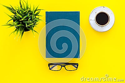 Book with empty cover near glasses, coffe, plant on yellow desk top view space for text. Spend time reading. Self Stock Photo