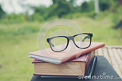 Book and eye glasses for read and write over blurred nature outdoor background. Stock Photo