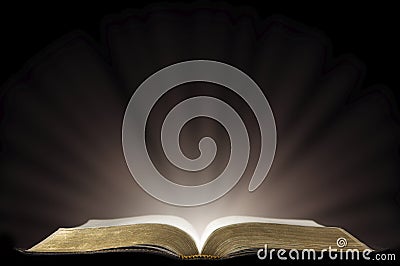 A Book that looks like a Bible Open in a Dark Room Stock Photo