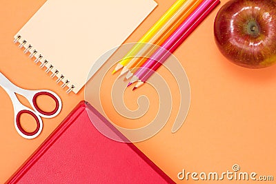 Book, scissors, notebook, color pencils and red apple on pink ba Stock Photo