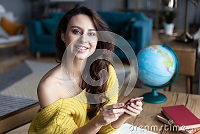 Book travel online. Portrait of a woman with a smartphone at home Stock Photo