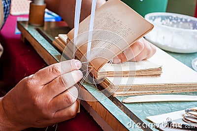 Bookbinding. Male worker binding pages. Stock Photo