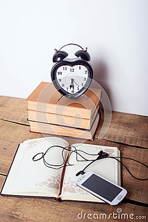 Books, alarm clock, notepad, cellphone with earphones on wooden background Stock Photo