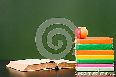 Books with apple near empty green chalkboard. Sample for text Stock Photo
