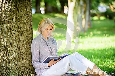 Books every girl should read. Girl concentrated sit park lean tree trunk read book. Reading inspiring books. Bestseller Stock Photo