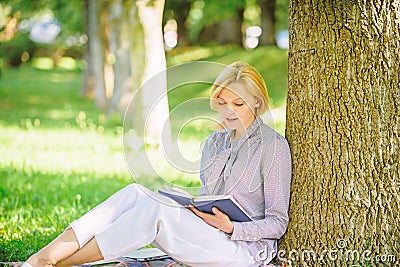 Books every girl should read. Girl concentrated sit park lean tree trunk read book. Reading inspiring books. Bestseller Stock Photo