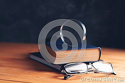 Books, magnifying glass and glasses on the table Stock Photo