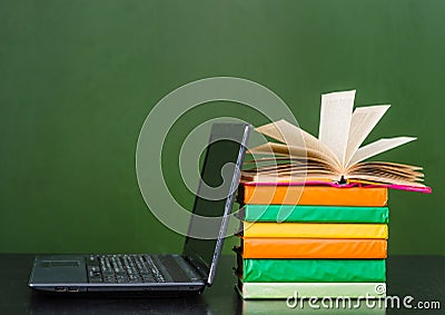 Books and notebook near empty green chalkboard. Sample for text Stock Photo