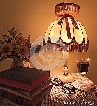 Books, wine, flowers, a discreet light lamp, glasses. Quiet evening at home Stock Photo