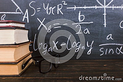 Books on a wooden table, against the background of a chalk board with formulas. Teacher's day concept and back to school Stock Photo