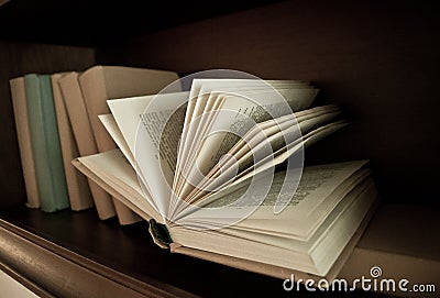 Bookshelf with books, one book lying open Stock Photo